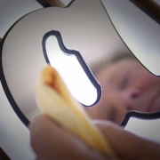 Close-up of a person cleaning a backlit metal yacht emblem or sign, polishing the illuminated surface with a cloth.
