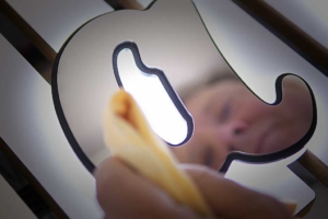 Close-up of a person cleaning a backlit metal yacht emblem or sign, polishing the illuminated surface with a cloth.