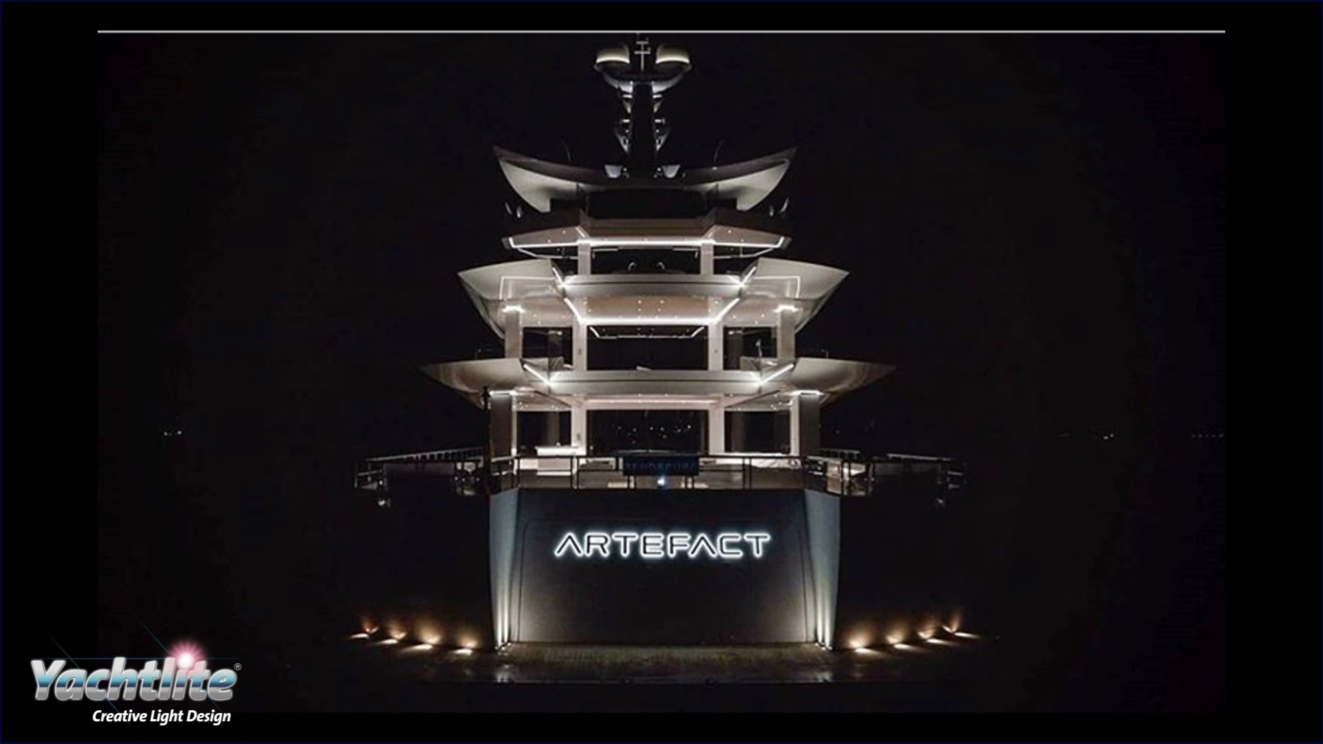 The stern of a large yacht at night, lit up by atmospheric lighting
